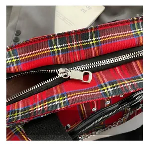 Detailed close-up of a silver metal zipper and hardware on a red plaid tote bag