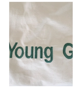 Detailed macro view of green Young G embroidery on high-quality white twill canvas fabric
