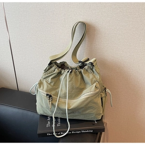 Detail of light green drawstring shoulder bag with pleated texture and adjustable strap