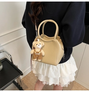 Détail du sac seau en cuir beige grainé avec un joli porte-clés ours en peluche
