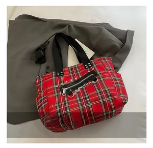 Detail of red plaid tote bag with silver metal chains and black canvas straps