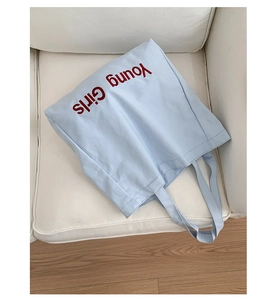 Close-up of light blue cotton canvas tote bag with red Young Girls text print