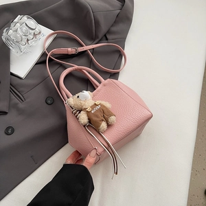 Détail d'un mini sac rose en cuir grainé avec une adorable breloque ours suspendue