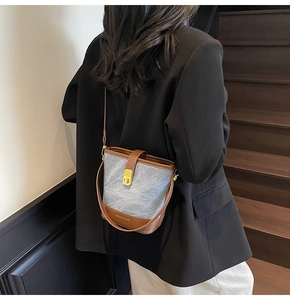 Detailed back view of a grey bucket bag with brown leather trim and gold hardware