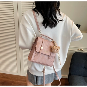 Pink crocodile-textured crossbody bag detail with golden hardware and brown bear charm