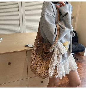 Détail d'un sac cabas tressé marron avec un nœud en dentelle blanche et des fleurs