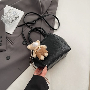 Détail du sac seau en cuir noir avec charmant ours en peluche et bandoulière longue
