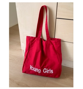 Detail view of red canvas tote bag showing Young Girls letter print and sturdy shoulder straps