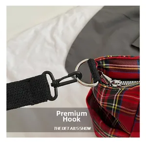 Close-up of durable black D-ring hook and zipper detail on red plaid tote bag