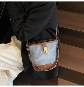 Detail of canvas bucket bag showing leather trim and elegant golden turn-lock closure