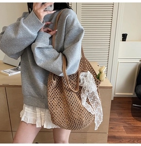 Détail d'un sac cabas tressé marron avec maille ajourée et ruban en dentelle blanche