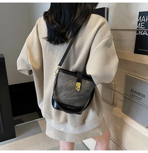 Detail of charcoal grey bucket bag showing golden twist lock and fashion lettering