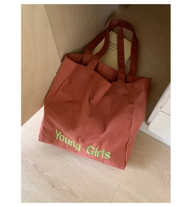Detailed close-up of terracotta canvas tote bag with neon green Young Girls lettering print