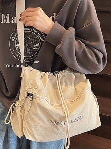 Minimalist beige nylon drawstring crossbody bag with textured pleats and shoulder strap