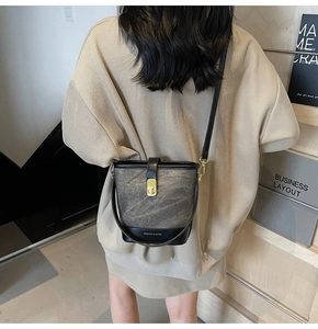 Detail of grey marble bucket bag with black leather trim and golden metal rotary lock
