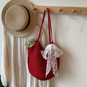 Détail d'un sac fourre-tout en crochet rouge avec nœud en dentelle et marguerite