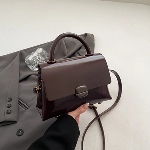 Detail of burgundy matte leather handbag featuring top handle and adjustable shoulder strap