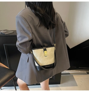 Detail of minimalist bucket bag showing golden twist lock and textured beige leather finish