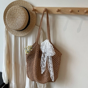 Détail du sac cabas en crochet marron tissé ajouré avec nœud en dentelle blanche brodé