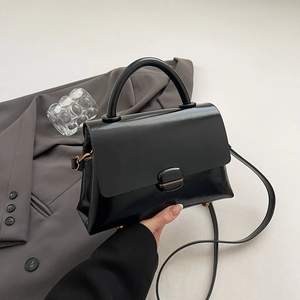 Detail of minimalist black leather crossbody bag with square buckle and top handle