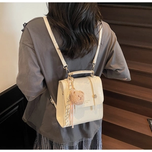 Detail of cream crocodile textured mini backpack with cute teddy bear and tassel charm