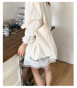 Close-up of green Young Girls embroidery on casual off-white canvas tote bag
