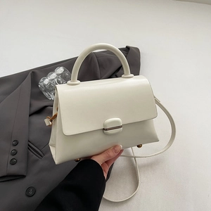 Detail of creamy white leather handbag with decorative square metal clasp and hand grip