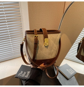 Detail of canvas bucket bag with brown leather trim and golden metal lock clasp