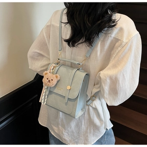 Detail of light blue crocodile texture bag with cute bear charm and gold magnetic clasp