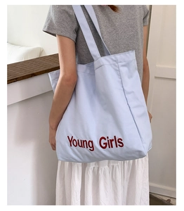 Close-up of light blue canvas tote bag with Young Girls red embroidery detail