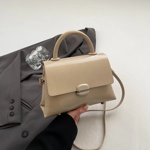 Detail of minimalist beige PU leather handbag with metallic square lock and round handle