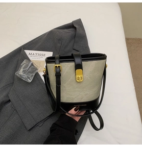 Dettaglio della borsa a secchiello bicolore con chiusura dorata e base con marchio