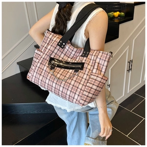 Detail of pink plaid tote bag showing the black zipper pocket and silver metal chain accessory