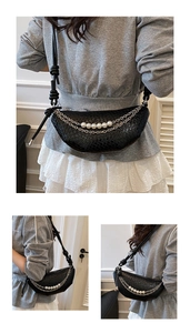 Close-up of black woven crescent bag featuring pearl chain details and knotted strap design
