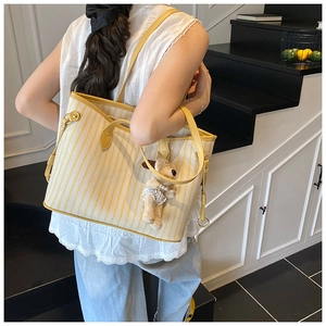 Detail of yellow striped tote bag with cute puppy plush charm on indoor staircase