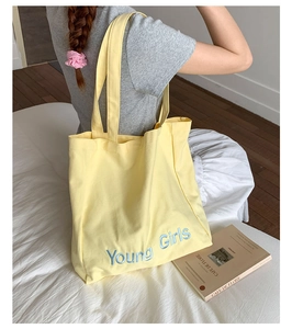 Detail of blue Young Girls letter embroidery on yellow canvas tote bag