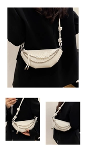 Detail of white woven crescent bag with silver chain and elegant pearl strap accents