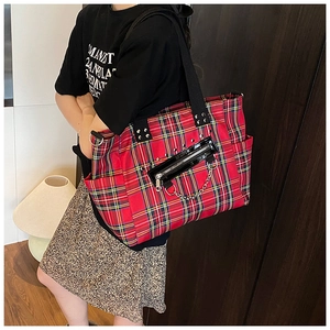Detail of red and black plaid tote bag with silver studs and punk metal chain