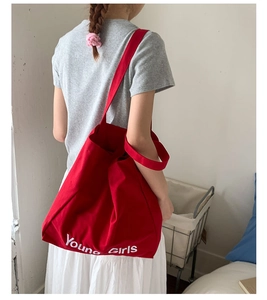 Rear view of a red large canvas tote bag with white lettering for casual daily use