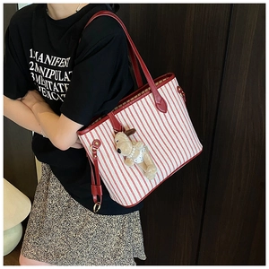 Detail of red and white striped tote bag featuring red leather straps and plush charm