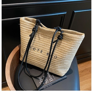 Detailed view of beige woven tote bag featuring black text and rope handles on a chair