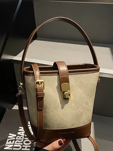 Minimalist beige canvas and brown leather bucket bag with adjustable strap and top handle