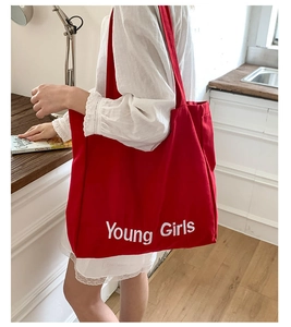 Side view of large red canvas tote bag with Young Girls print on shoulder of a model