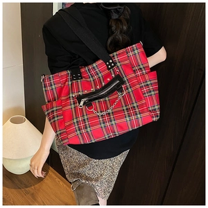 Detail of red plaid tote bag with silver chain and wide black shoulder strap