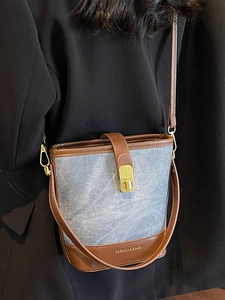 Blue denim and brown leather bucket bag with gold buckle shown on a female model
