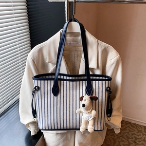 Detail of blue and white striped canvas tote bag with a small dog plush pendant accessory