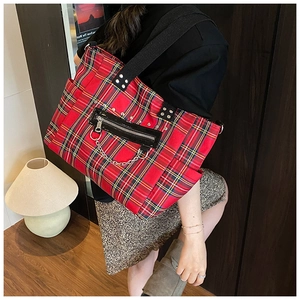 Macro view of punk style tote bag with red tartan pattern, silver metal rivets and chains