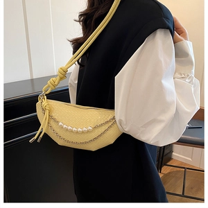 Detailed view of yellow woven half-moon bag with pearl strap and knotted shoulder strap