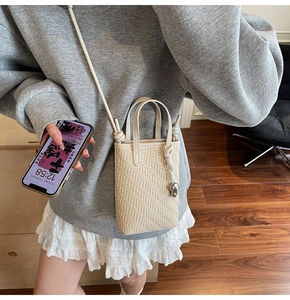 Detailed view of beige woven mini crossbody bag with herringbone texture and dual handles