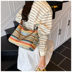 Close-up of a colorful woven crossbody bag with metallic chain strap for summer style